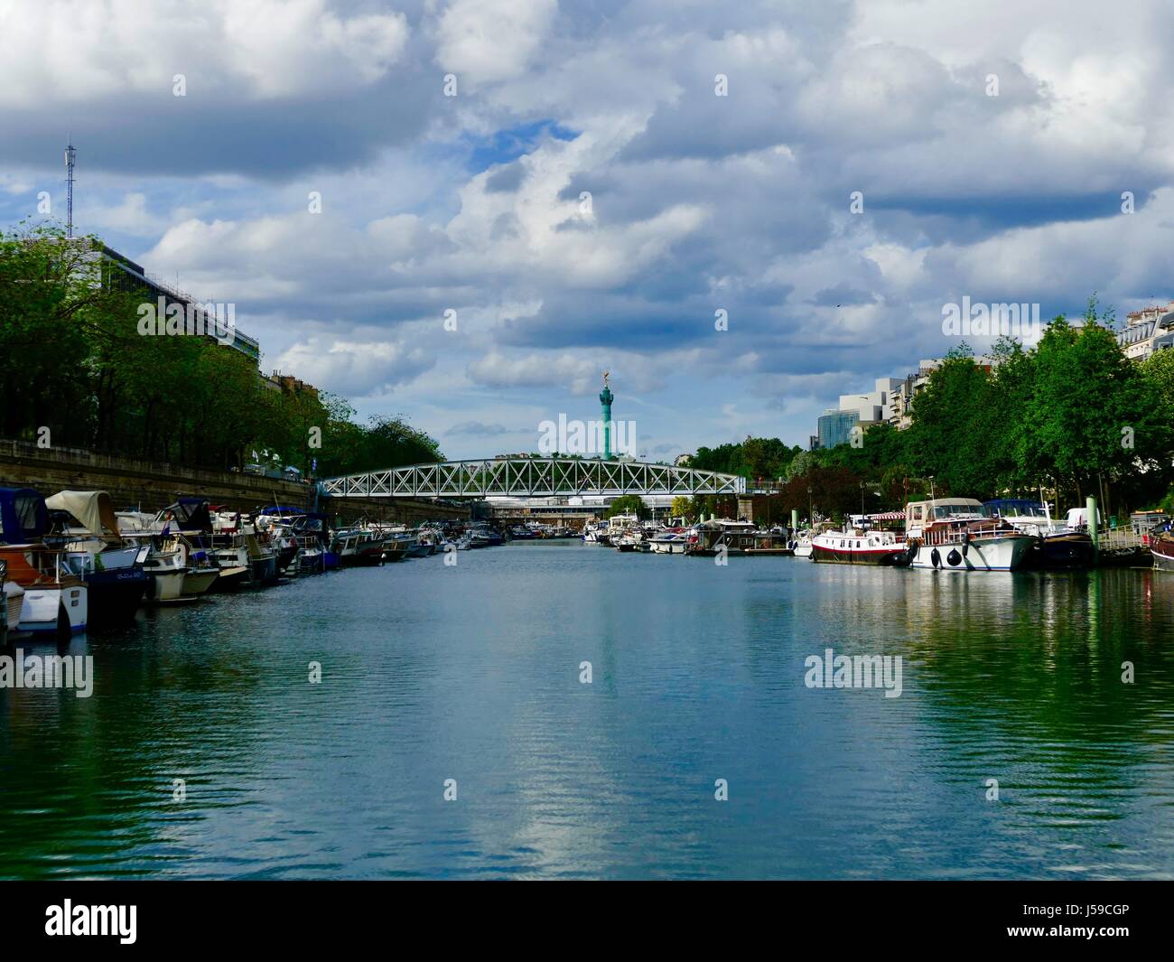 Bassin de l'arsenal avec la Colonne de Juillet, Colonne de Juillet, dans la distance et un pont pour piétons à l'avant-plan. Paris France Banque D'Images
