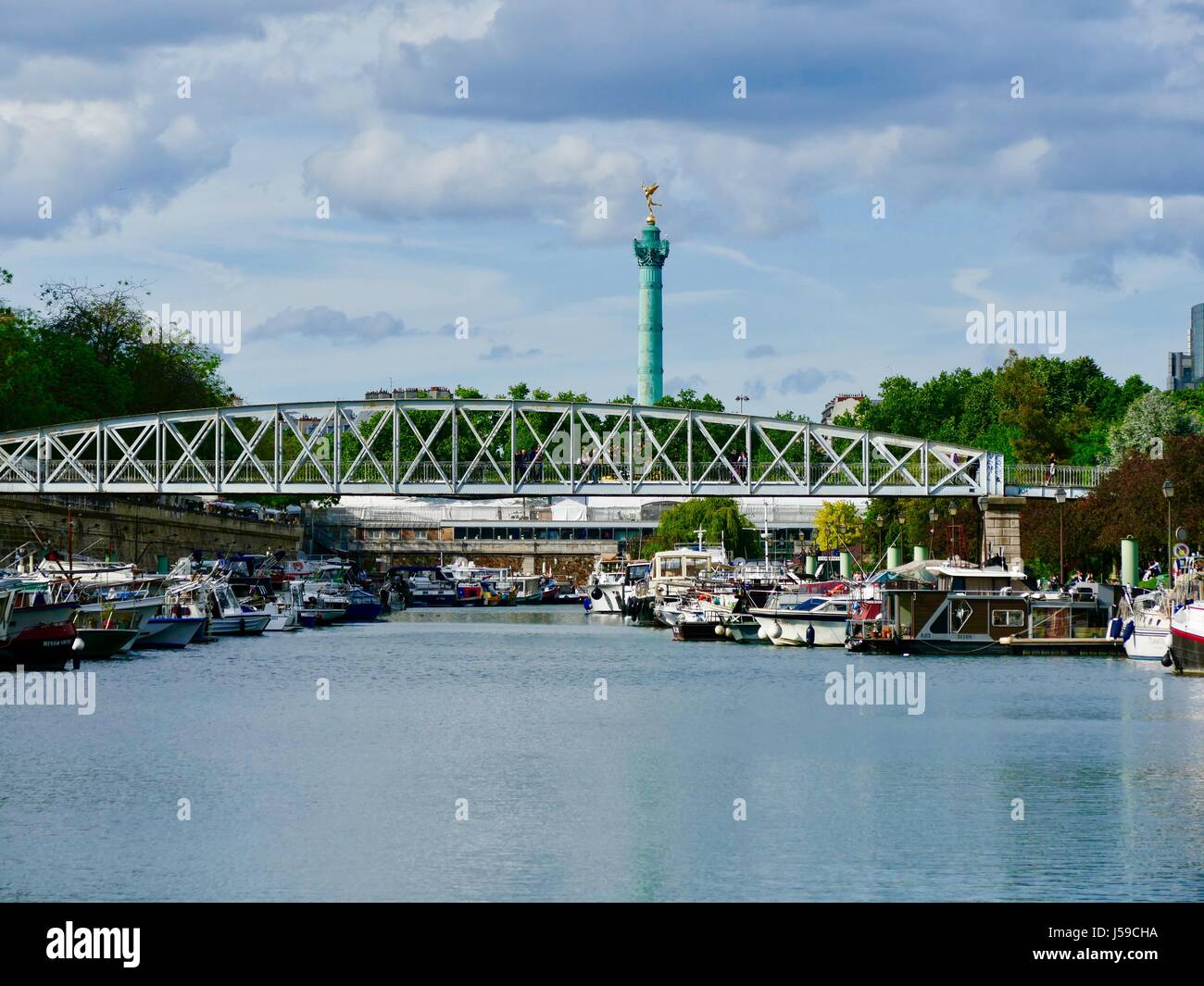 Bassin de l'arsenal avec la Colonne de Juillet, Colonne de Juillet, dans la distance et un pont pour piétons à l'avant-plan. Paris France Banque D'Images