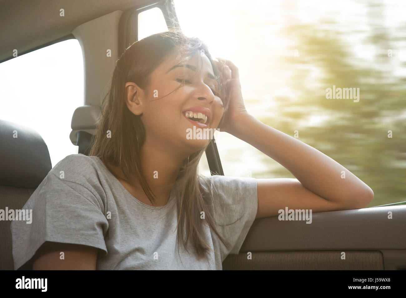 Heureux les jeunes femmes dans les cheveux de voiture est soufflé par le vent Banque D'Images
