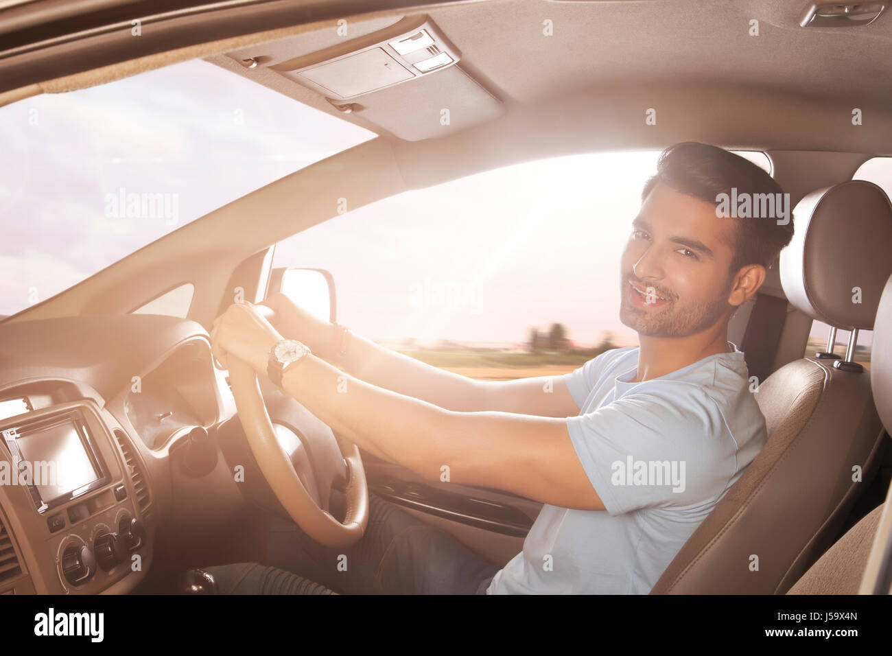 Smiling young man driving a car Banque D'Images