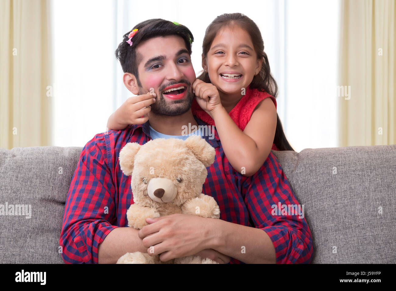 Père maquillés jusqu'posing with daughter holding teddy bear Banque D'Images