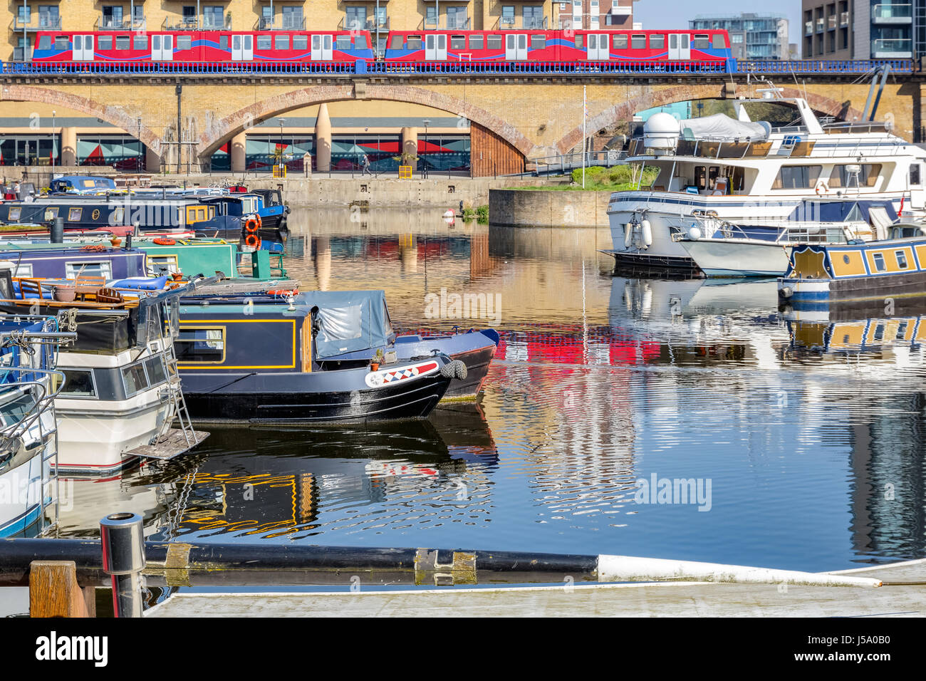 Bateaux et yachts amarrés au port de plaisance du bassin de Limehouse à Londres avec un train passant par en arrière-plan Banque D'Images