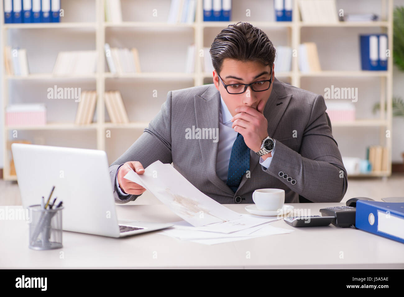 Businessman de renverser du café sur des documents importants Banque D'Images