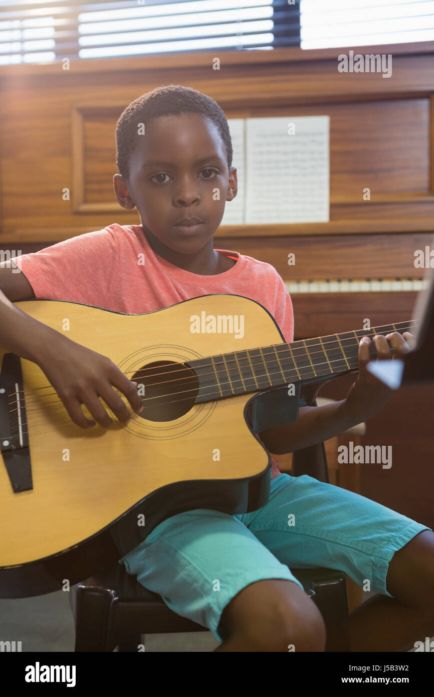 Portrait de jeune garçon qui joue de la guitare en classe à l'école de musique Banque D'Images