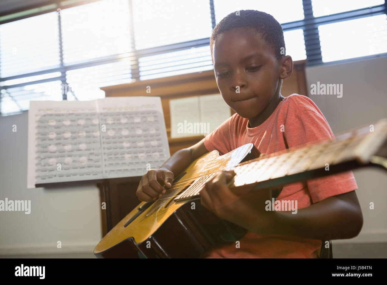 Garçon qui joue de la guitare en classe à l'école de musique Banque D'Images