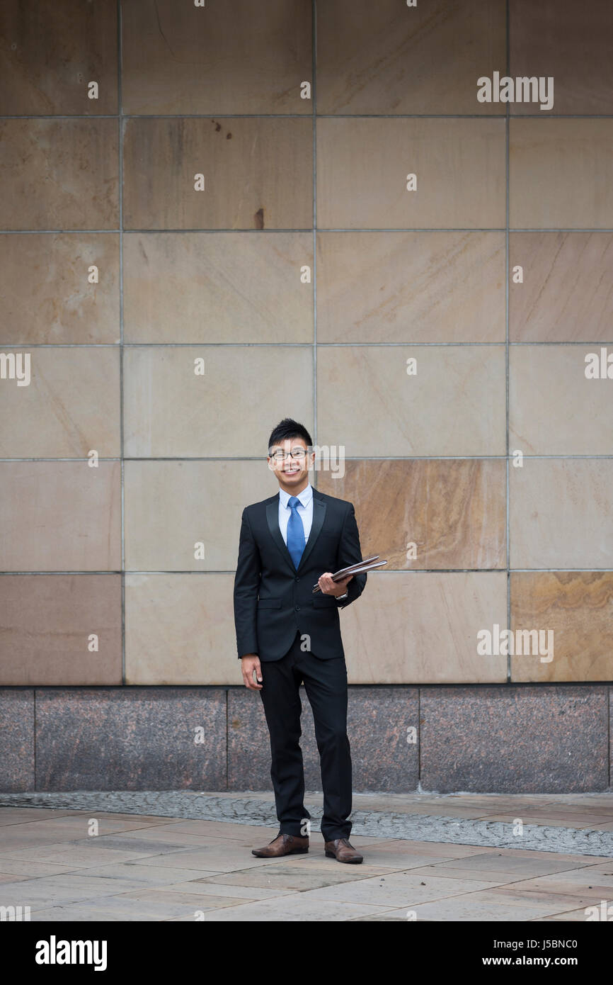 Portrait d'un homme d'affaires chinois à l'extérieur immeuble de bureaux modernes. Asian businessman smiling & regardant la caméra. Banque D'Images