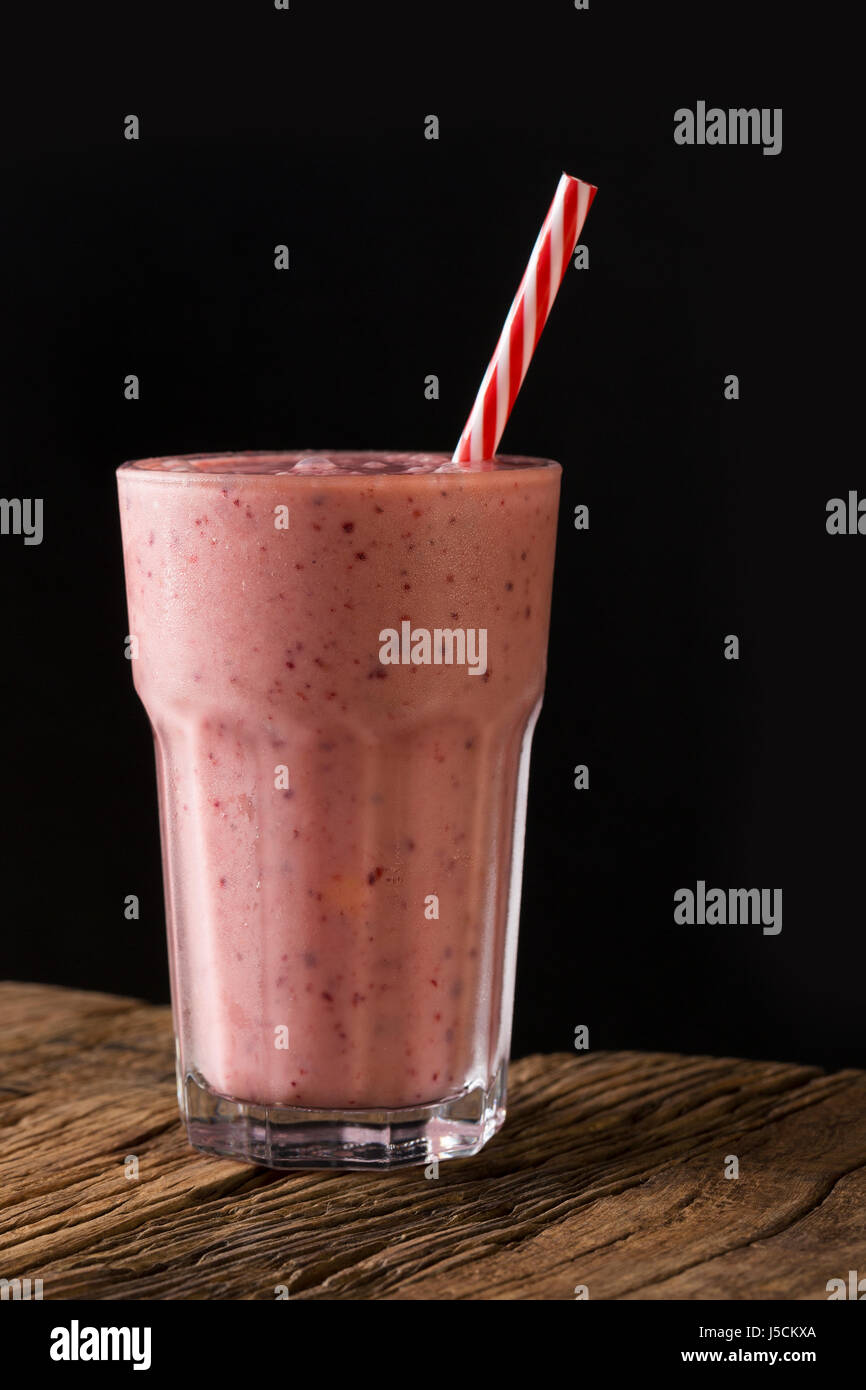 Un verre de smoothie aux petits fruits, sur un fond de bois rustique. Banque D'Images