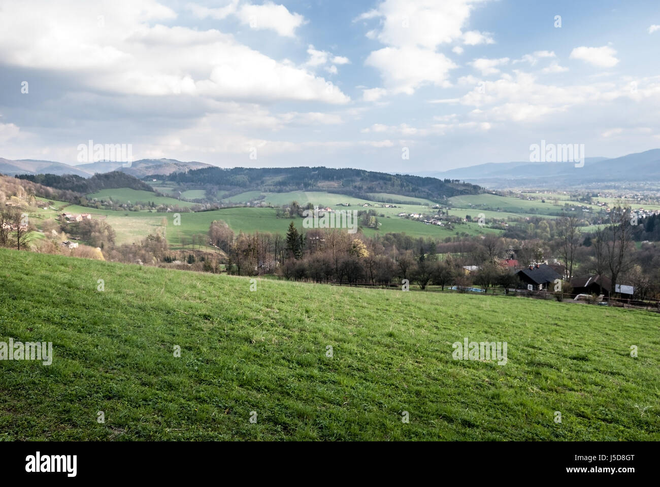 Campagne de printemps des montagnes beskides près de venndryne village en République tchèque avec des prairies, maisons, collines et ciel bleu avec des nuages Banque D'Images