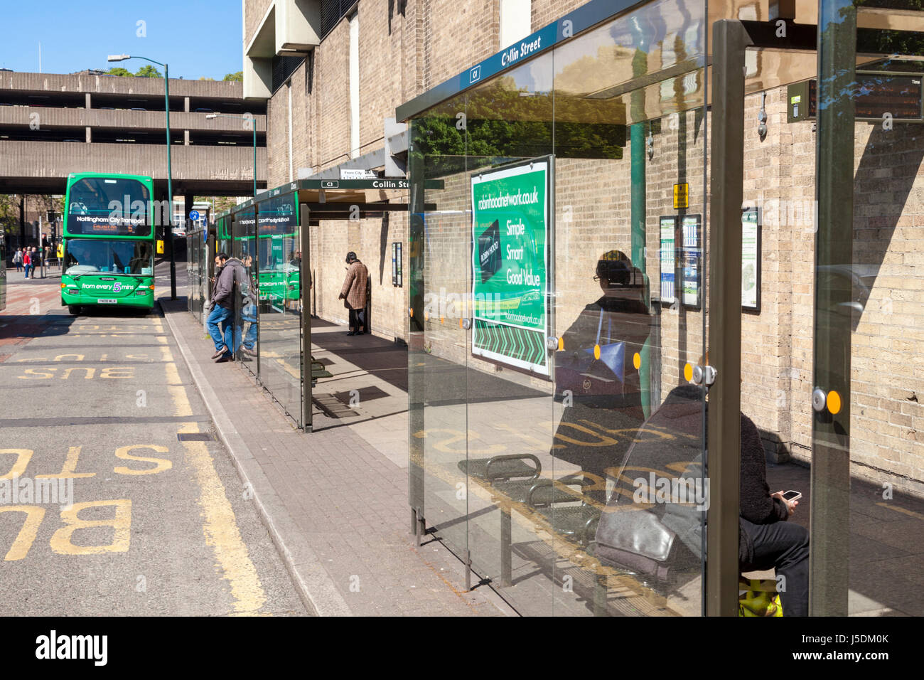 Les gens qui attendent à un arrêt de bus. Une section d'une rue avec plusieurs arrêts de bus desservant de nombreux services de bus, Nottingham, England, UK Banque D'Images