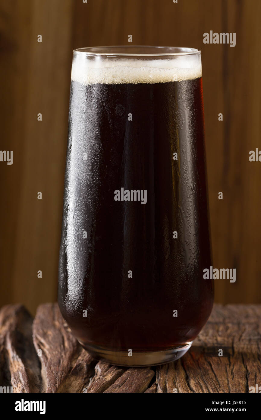 Une pinte de bière artisanale assis sur une barre en bois rustique. Porter des microbrasseries. Banque D'Images