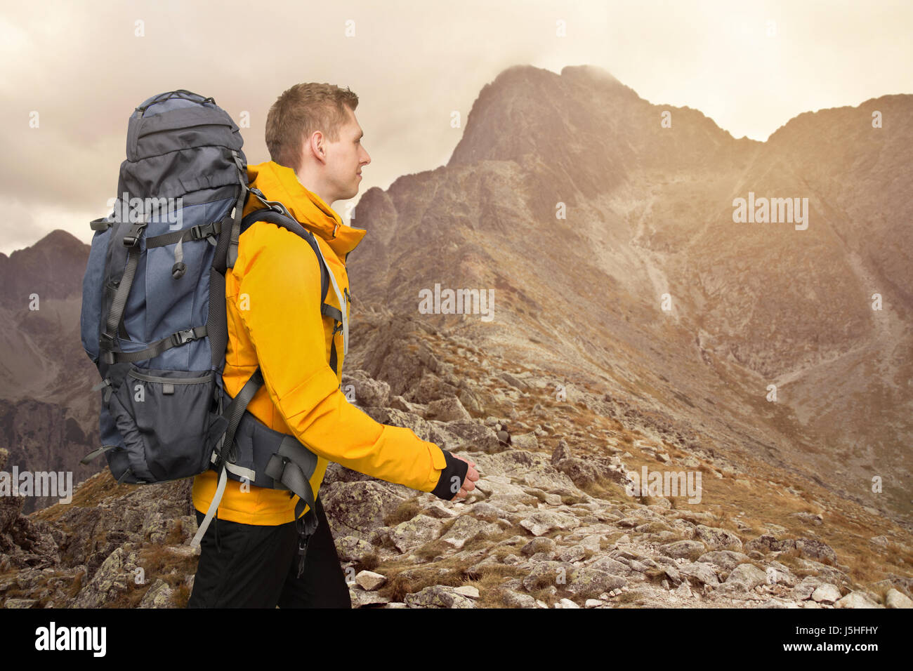 L'homme avec un grand sac à dos randonneur marchant dans les montagnes au coucher du soleil Banque D'Images