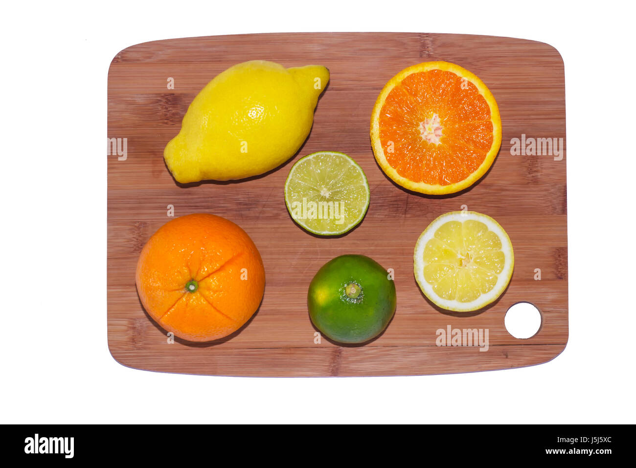 Une sélection de morceaux d'oranges, citrons et limes sur une planche en bois sur fond blanc. Banque D'Images