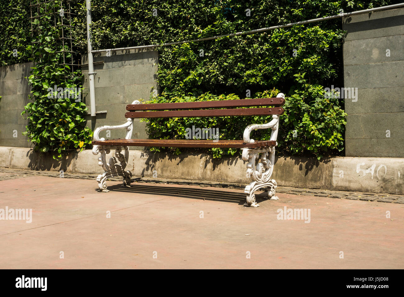 Banc sur le trottoir avec bush green tree comme arrière-plan Banque D'Images