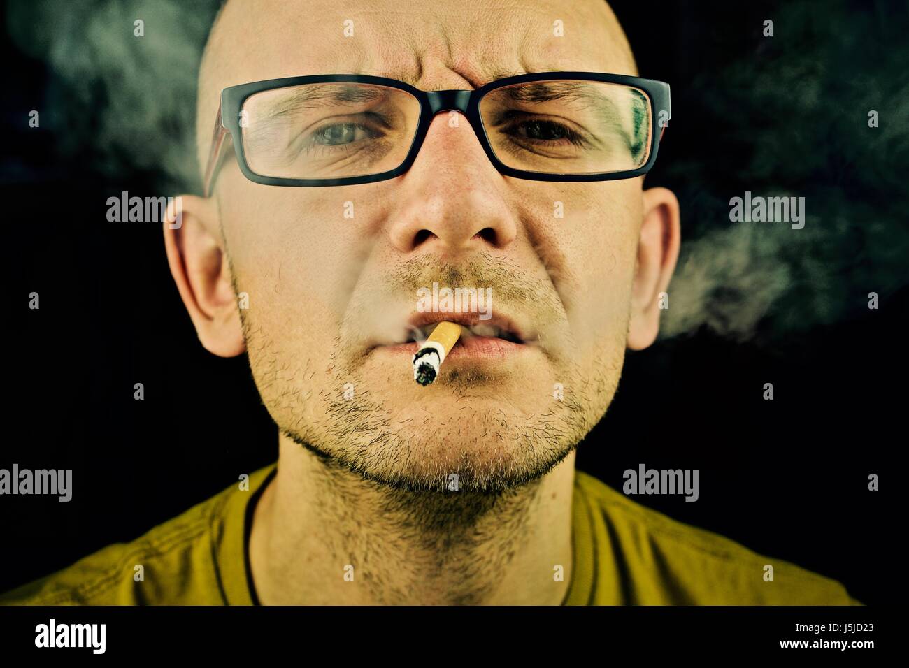 Jeune homme en t-shirt jaune de fumer la cigarette. Banque D'Images