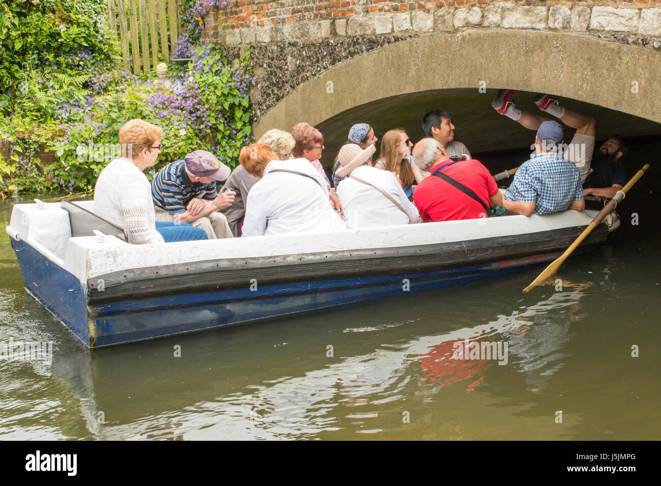 Un guide a pour se coucher sur son dos et utiliser ses pieds pour pousser un bateau dans un tunnel pendant un tour sur le fleuve Stour dans la ville de Canterbury. Banque D'Images