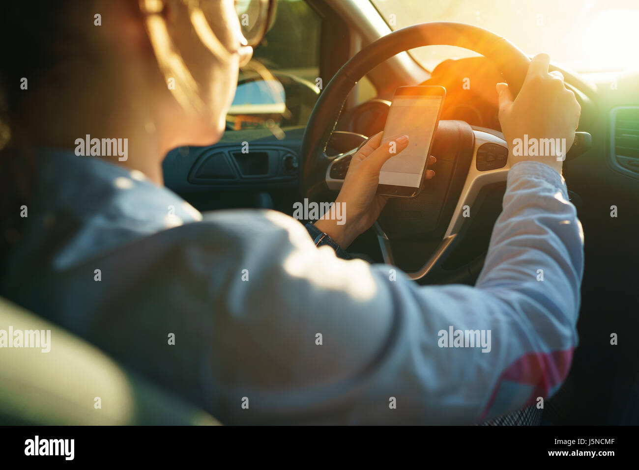 Femme utilise un navigateur dans un smartphone au volant d'une voiture Banque D'Images