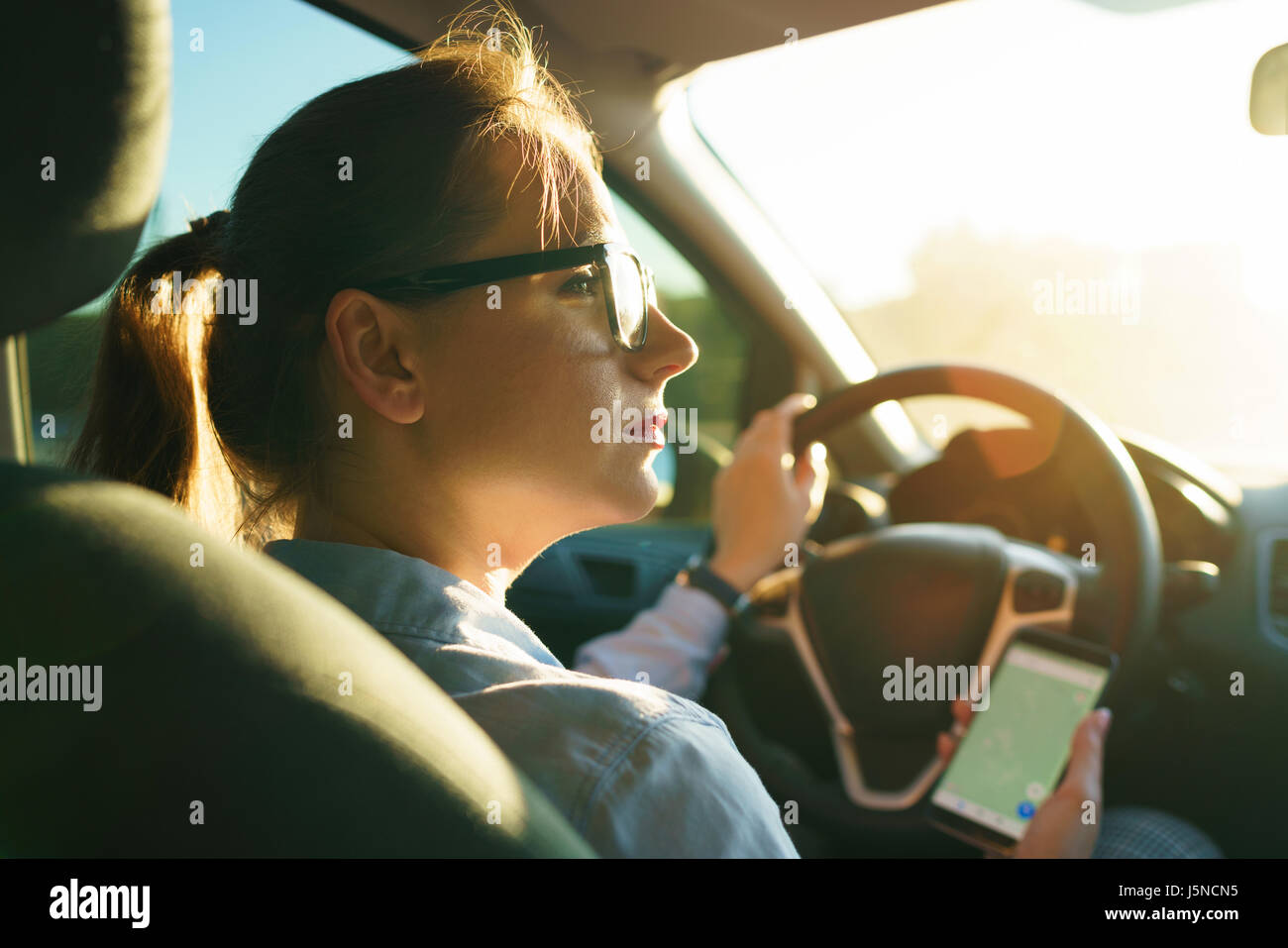 Femme utilise un navigateur dans un smartphone au volant d'une voiture Banque D'Images