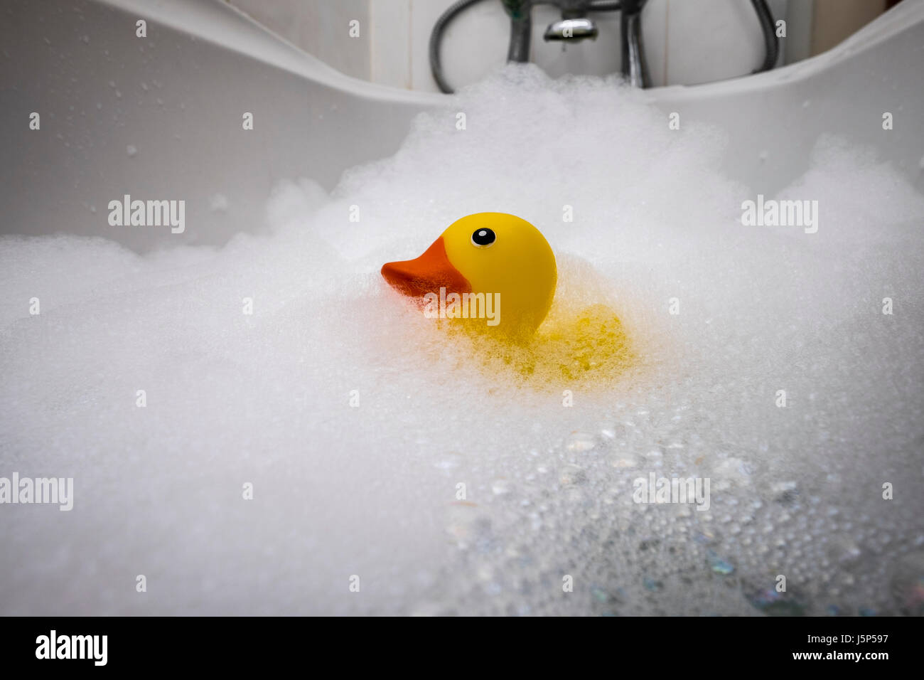 L'heure du bain, un canard en plastique dans un bain de mousse. Banque D'Images