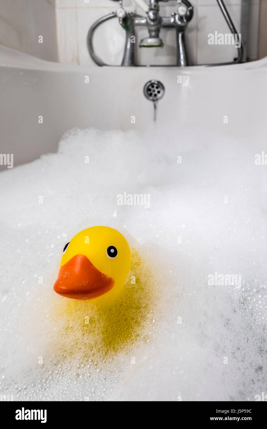 L'heure du bain, un canard en plastique dans un bain de mousse. Banque D'Images