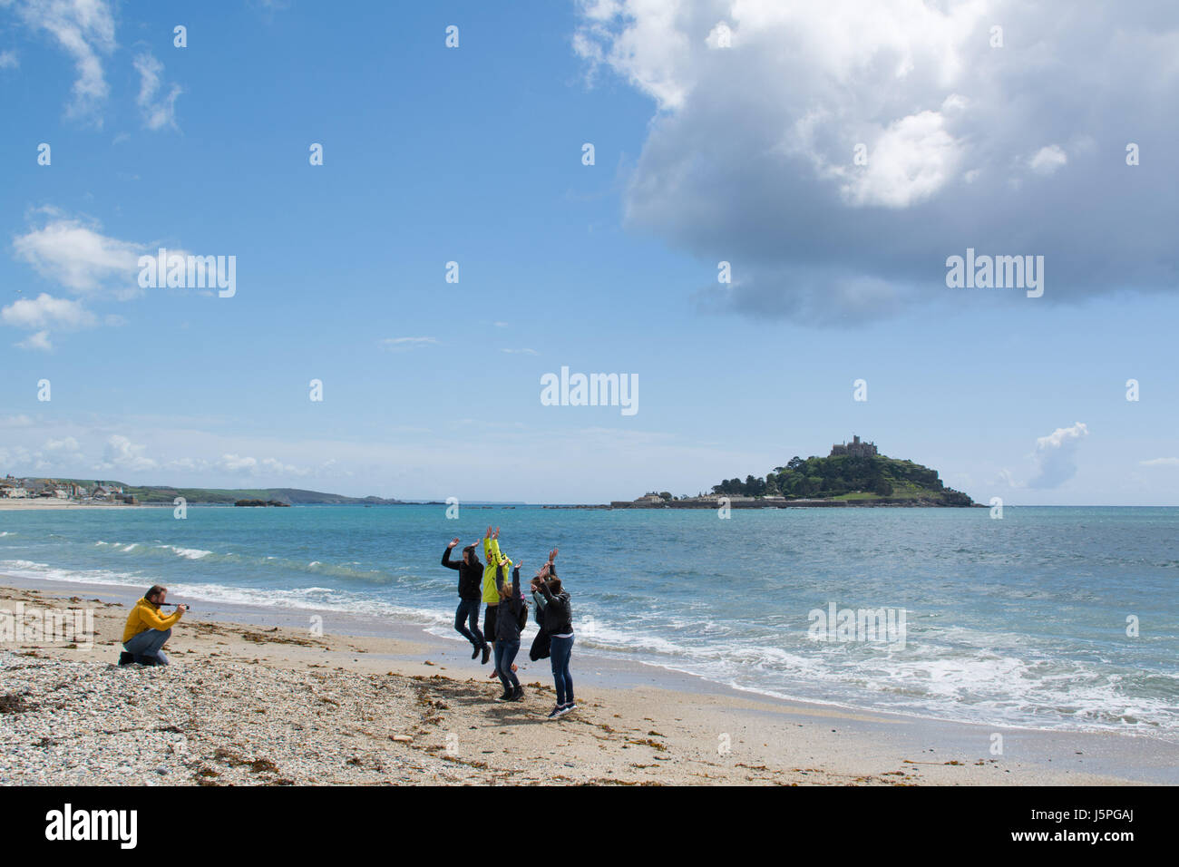 Marazion, Cornwall, UK. 18 mai 2017. Météo britannique. Un groupe de visiteurs européens à Cornwall, en profitant d'une brève période d'ensoleillement, sautant de leur maison de pic en face de St MIchaels Mount. Crédit : Simon Maycock/Alamy Live News Banque D'Images