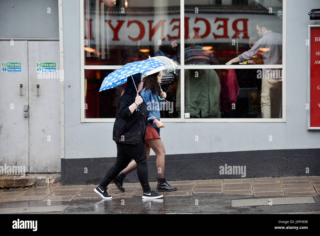 Brighton, UK. 18 mai, 2017. Les jeunes femmes reflète dans une fenêtre comme ils marchent dans la pluie torrentielle à travers le centre de Brighton aujourd'hui Crédit : Simon Dack/Alamy Live News Banque D'Images