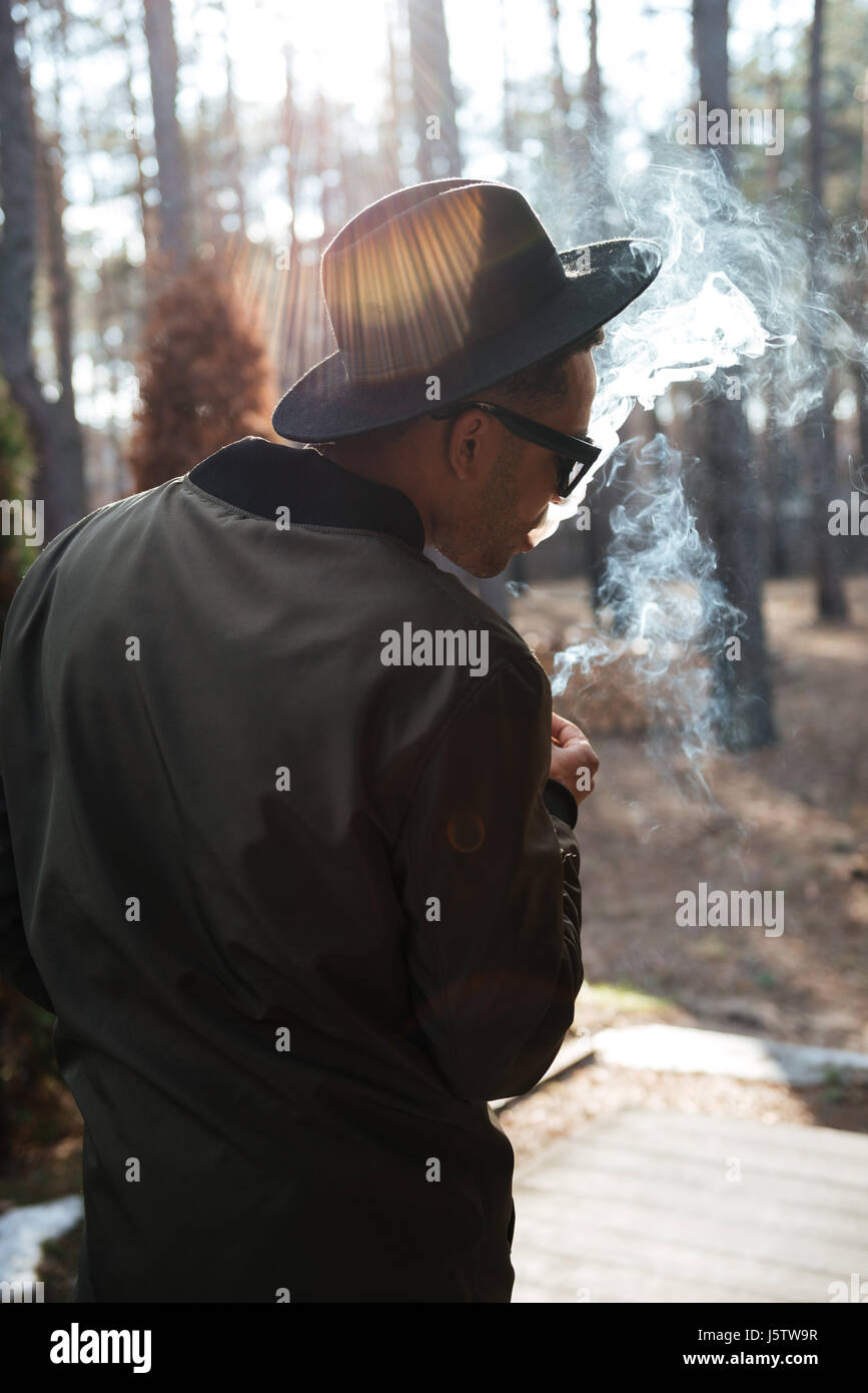 Vue arrière photo de african man standing en plein air dans la forêt de fumer. Banque D'Images