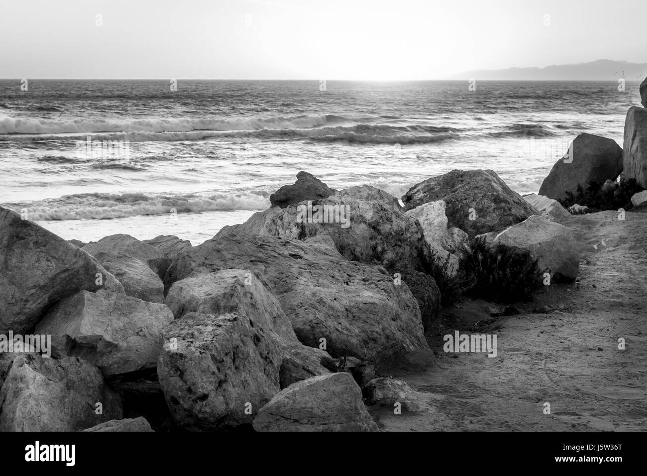 Photo en noir et blanc d'une plage au coucher du soleil. Banque D'Images