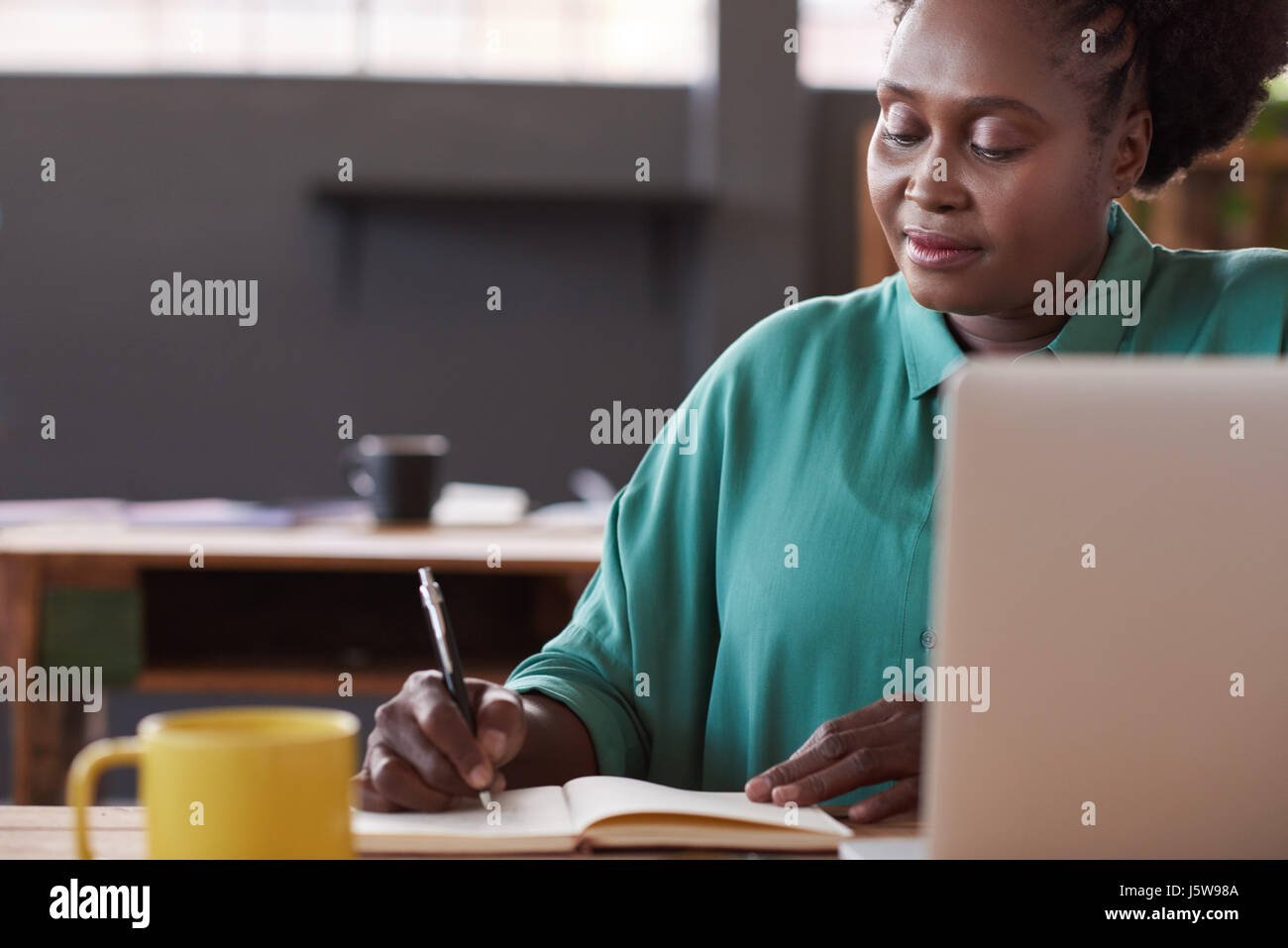 African businesswoman écrit dans un ordinateur portable à son bureau Banque D'Images