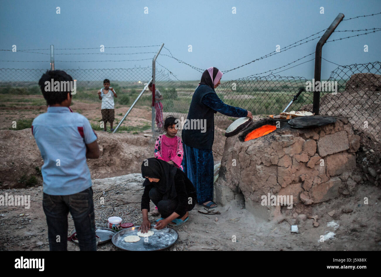 Une famille fait du pain dans un four de boue dans le camp de réfugiés de l'Irak, Khazir Banque D'Images