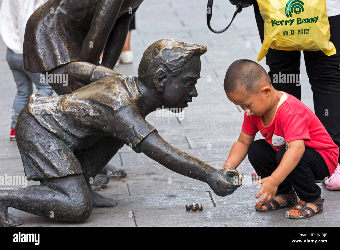 Garçon chinois jouant avec statue, Yinchuan, Ningxia, Chine Banque D'Images