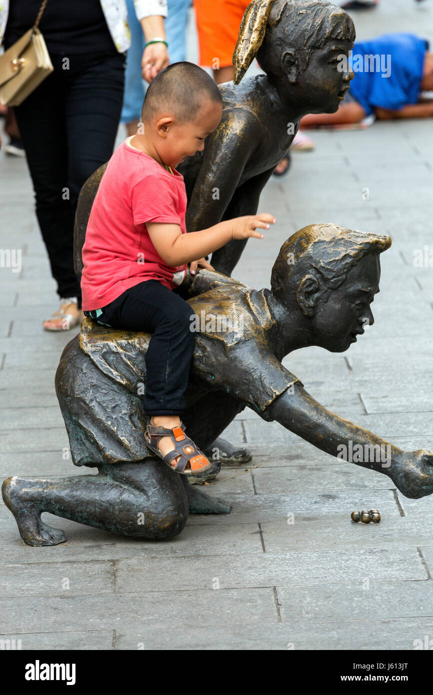 Garçon chinois jouant avec statue, Yinchuan, Ningxia, Chine Banque D'Images