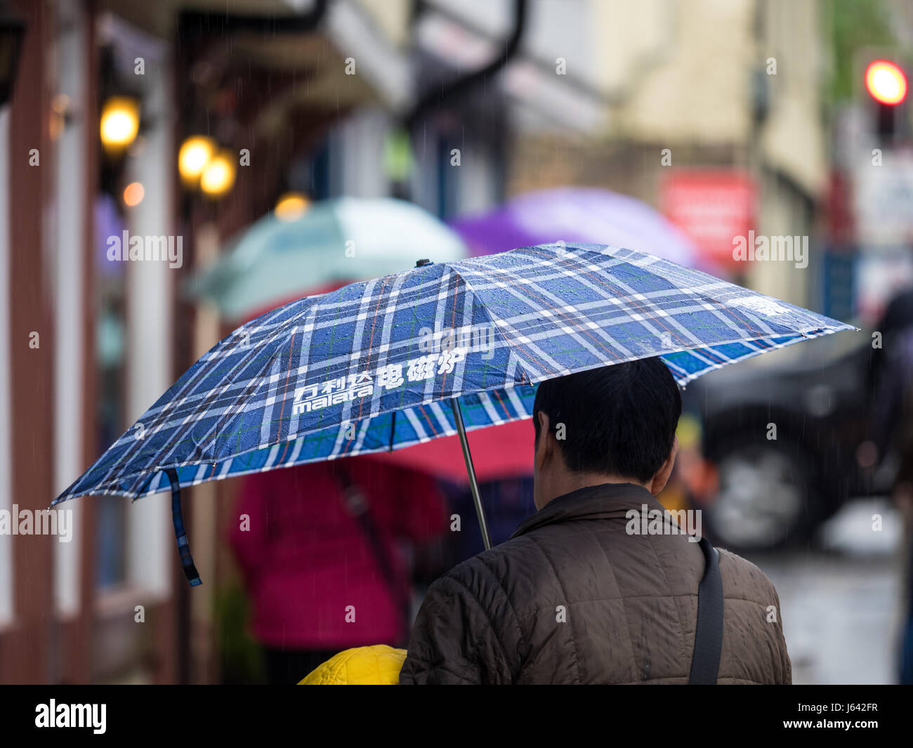Les touristes à l'abri sous les parasols à Cambridge, UK Banque D'Images