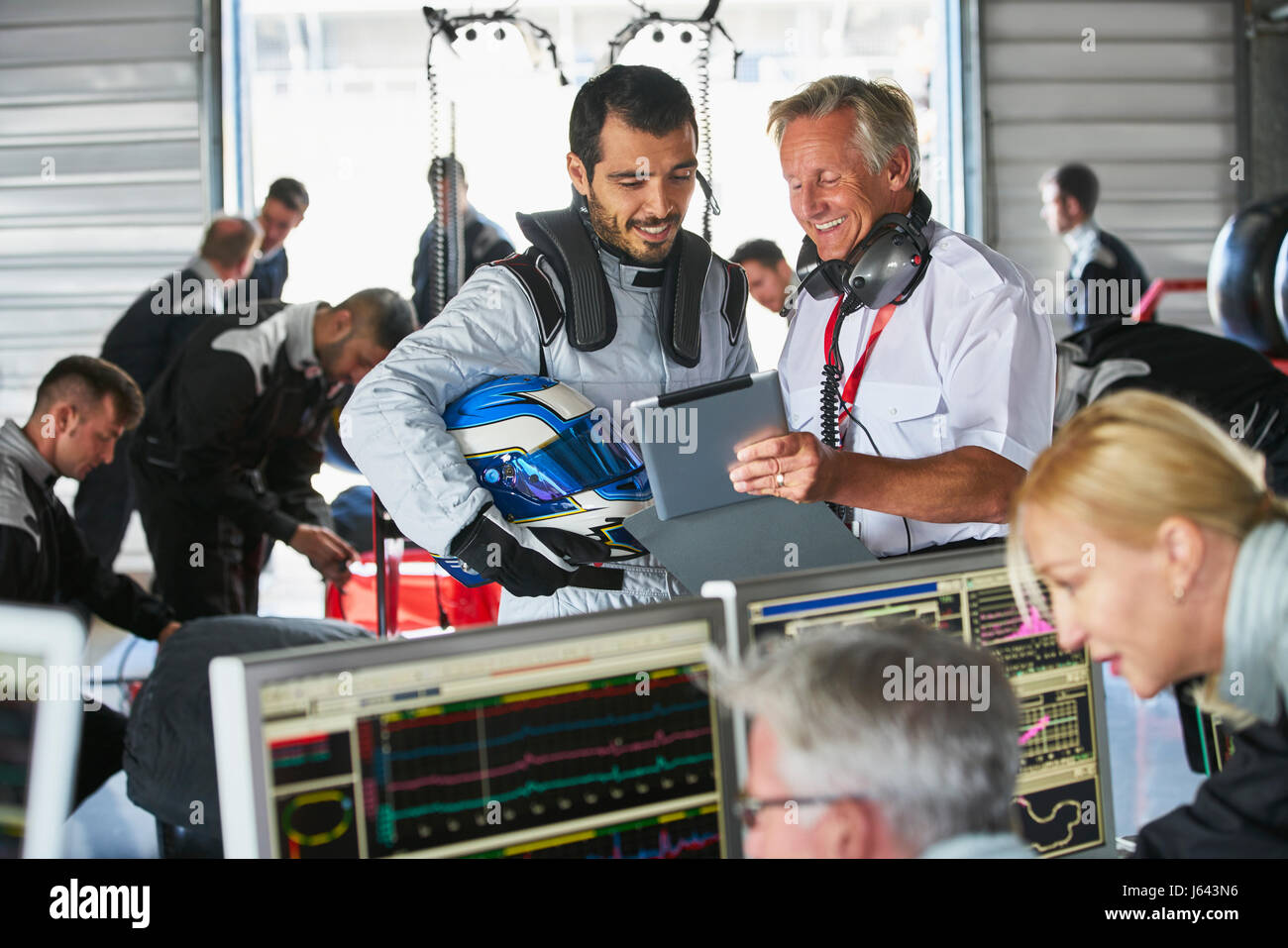 Manager et pilote de Formule 1 avec tablette numérique en parlant de réparation automobile Banque D'Images