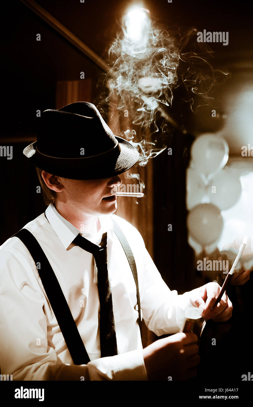 Séance mafieux et fumer un cigare à travers la fumée Banque D'Images