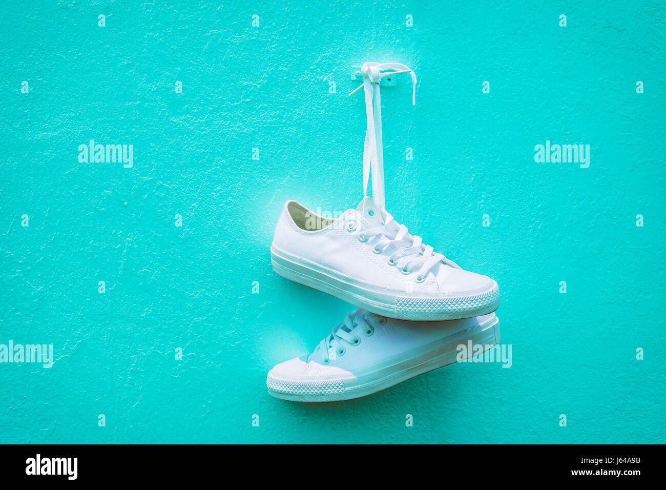 Sneakers blanc accroché contre le bleu des murs. Banque D'Images Sneakers blanc accroché contre le bleu des murs. Banque D'Images