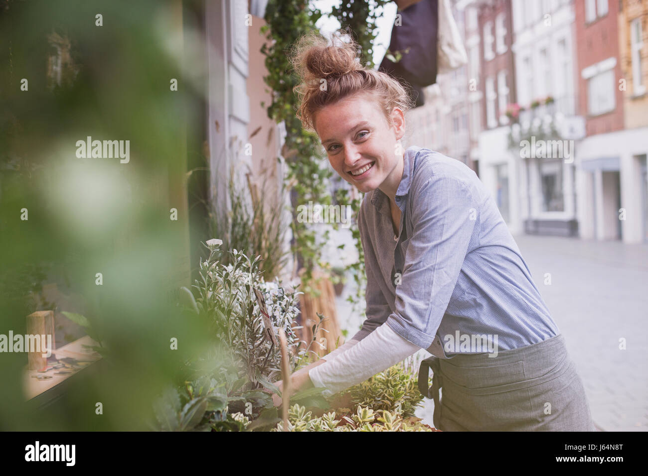 Portrait of smiling young female florist organiser l'affichage à l'storefront Banque D'Images