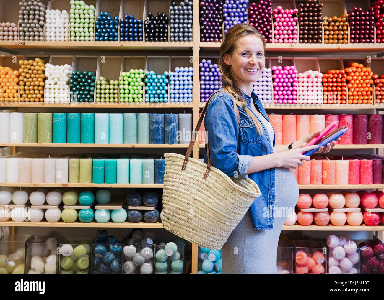 Portrait of smiling pregnant woman shopping for candles in shop Banque D'Images