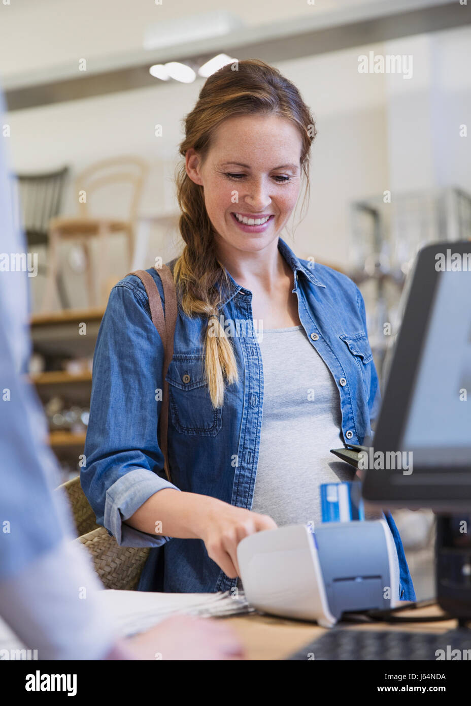 Smiling woman using credit card reader in shop Banque D'Images