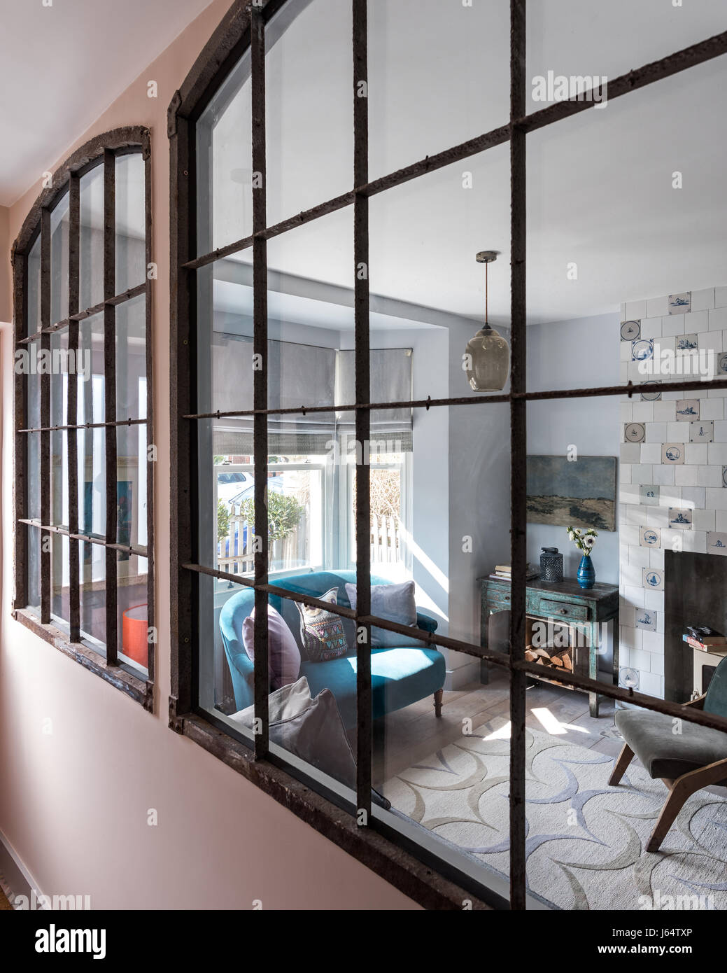 De grandes portes-fenêtres avec vue sur le métal récupéré par le biais d'un salon. Les carreaux autour de la cheminée sont Delft, le tapis est par Allegra Hicks et le s Banque D'Images