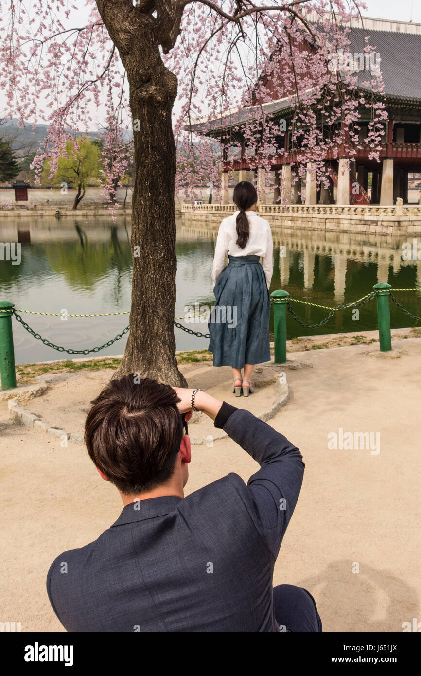 Un homme prenant des photos d'une femme dans le pavillon Gyeonghoeru à Gyongbokgung Palace, Séoul, Corée du Sud Banque D'Images