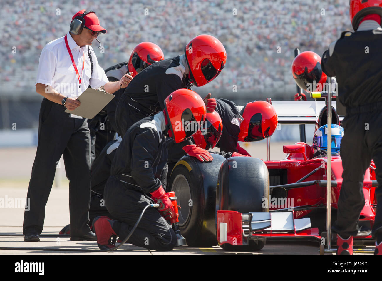 Manager avec chronomètre pit crew le remplacement des pneus de voiture de course de Formule 1 dans le pit lane Banque D'Images