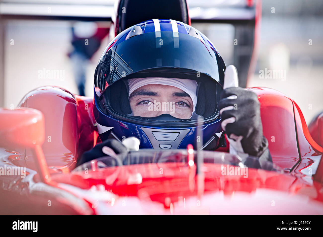 Portrait confiant homme formula one race car driver gesturing thumbs-up Banque D'Images
