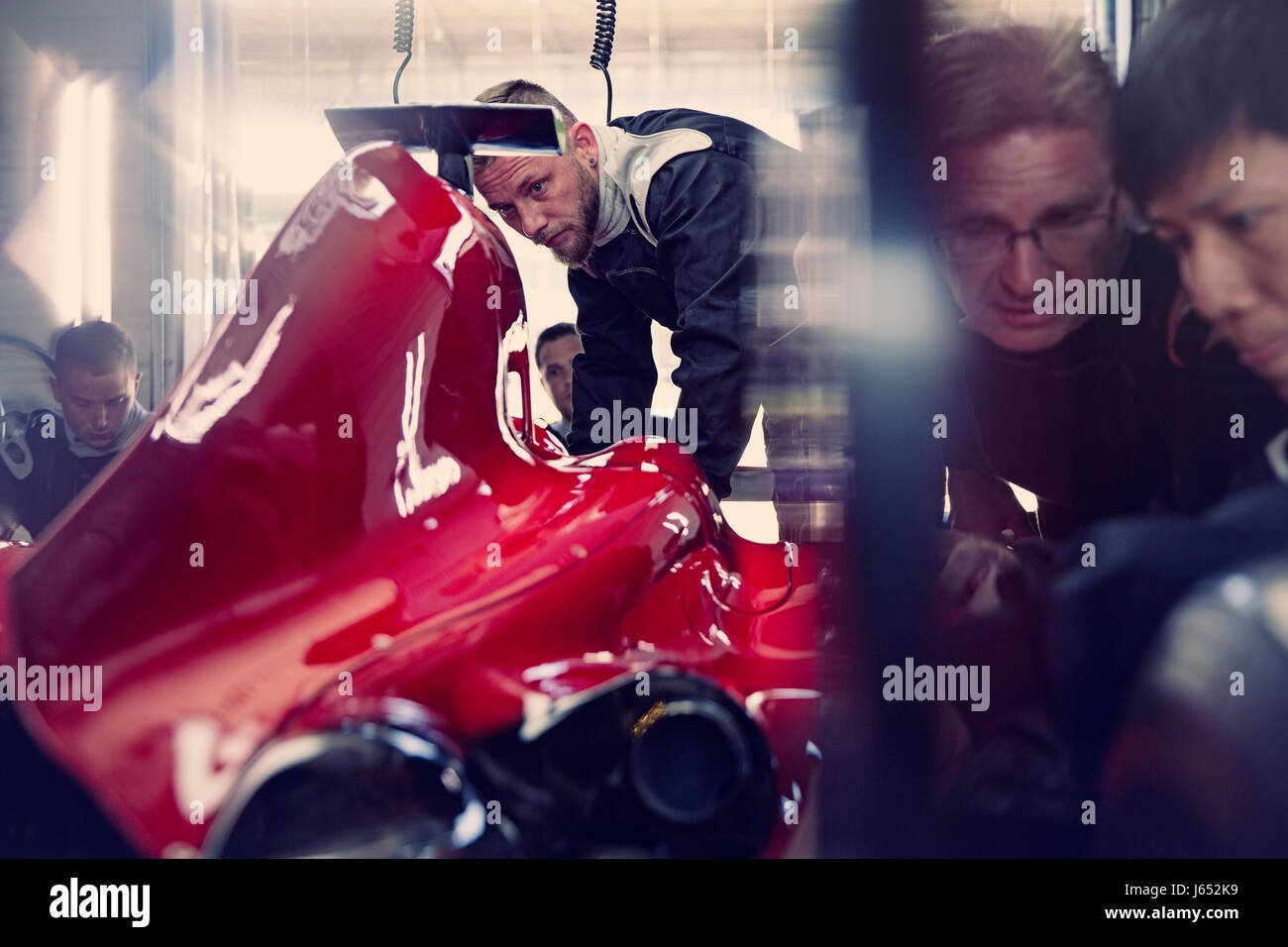 Pit Crew travaillant sur course de Formule 1 voiture dans un garage de réparation Banque D'Images
