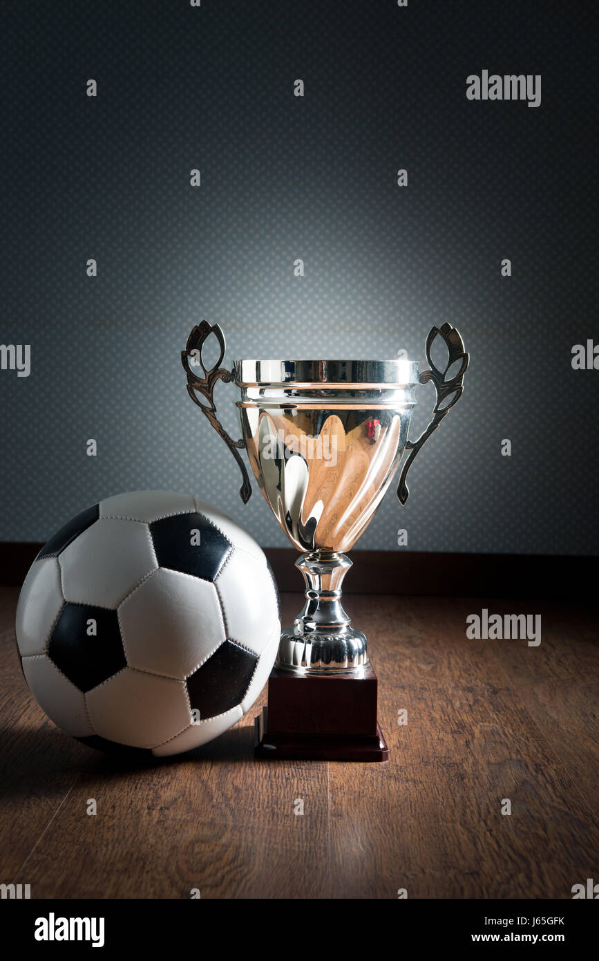Trophée de la coupe d'or et ballon de soccer sur plancher de bois franc, concept gagnant. Banque D'Images