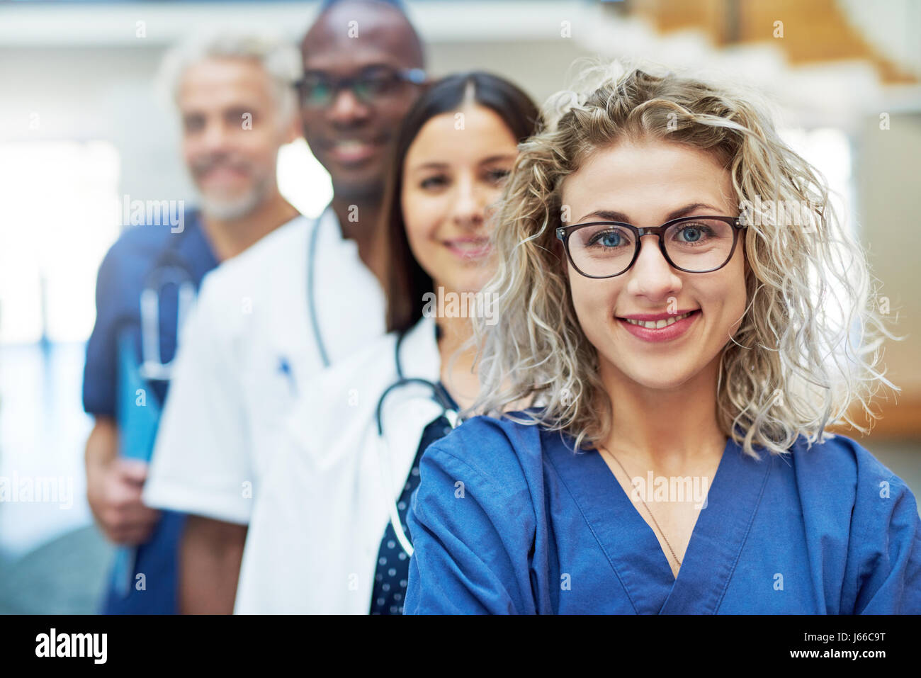 Comité permanent de l'équipe médecin multiethnique dans un hôpital et en regardant la caméra. Banque D'Images