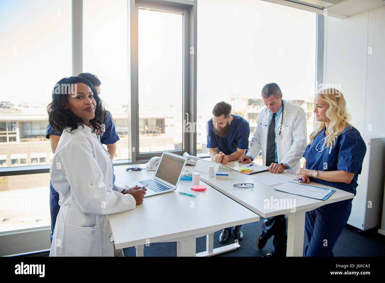 Black female doctor smiling at camera au cours d'une réunion avec d'autres médecins Banque D'Images