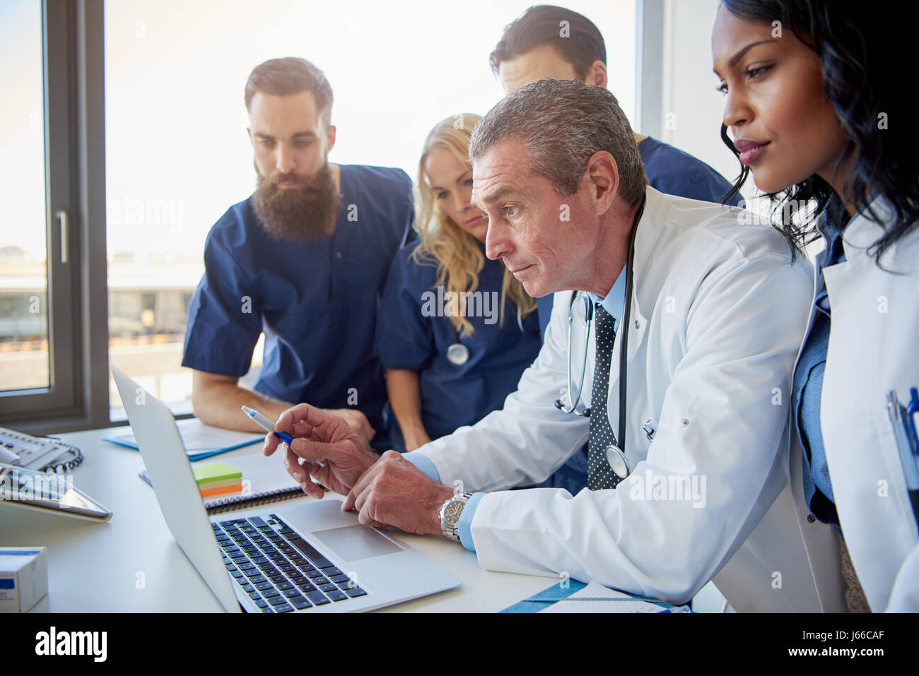 Équipe de médecins multiethnique looking at laptop lors de réunion à l'hôpital. Banque D'Images