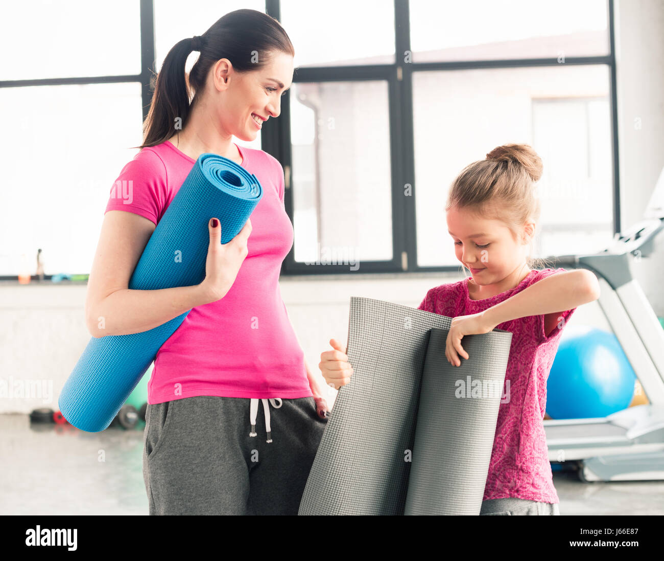 Mère et fille en rose shirts tenue de tapis de yoga en salle de sport Banque D'Images