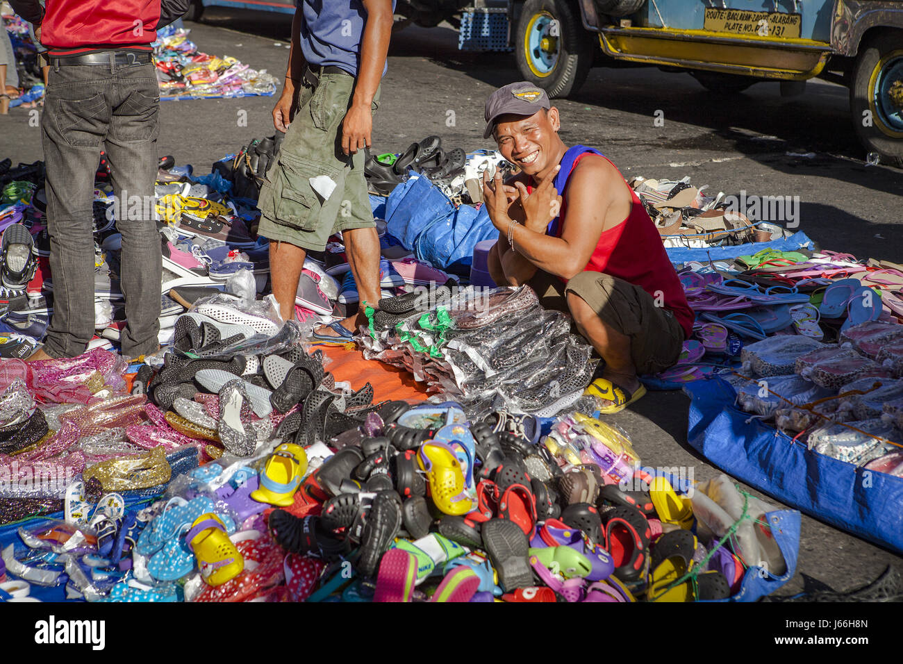Un vendeur vend côté rue, bon marché chaussures importées en plastique à l'open market à Baclaran, Manille, l'île de Luzon, aux Philippines. Banque D'Images