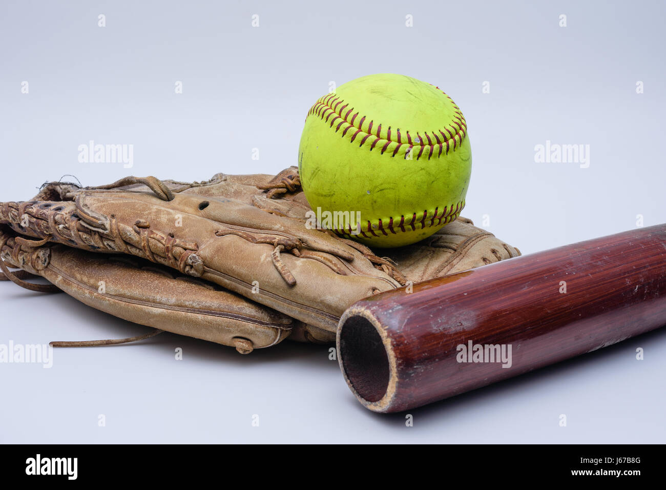 Le softball est assis sur de vieux gant avec bat Banque D'Images